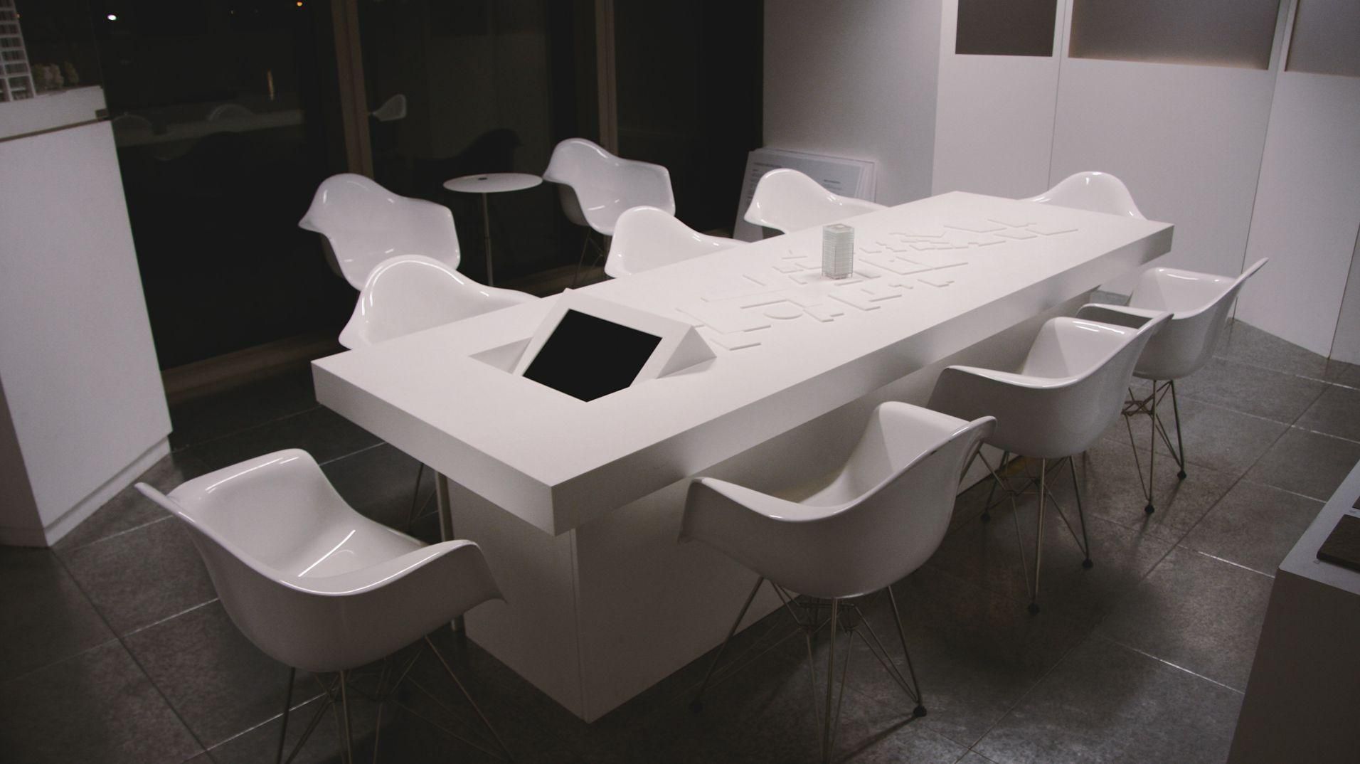 An overhead view of the white meeting table, chairs and embedded touchscreen.