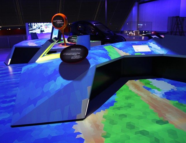 The angular central installation covered by a blue and green landscape projection.