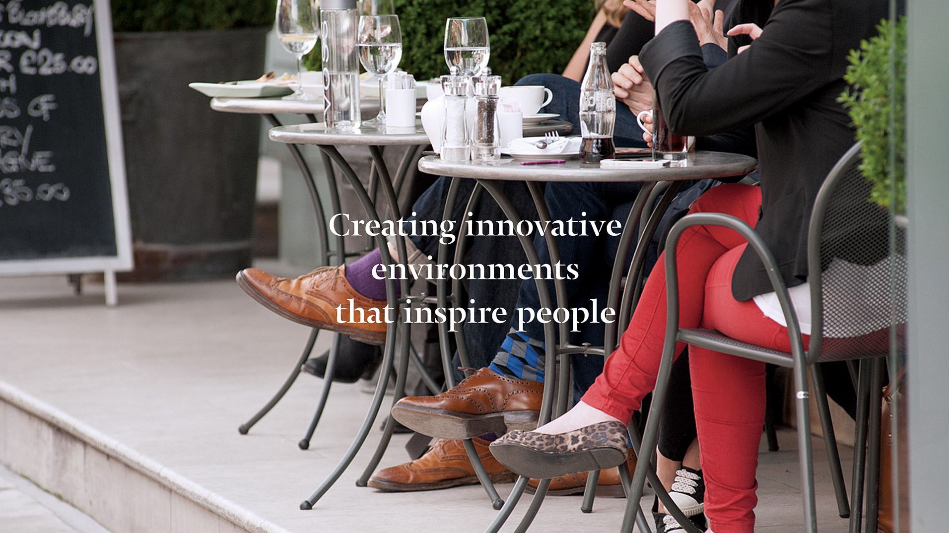 People seated outside a restaurant beneath Bruce Gillingham Pollard's brand message.