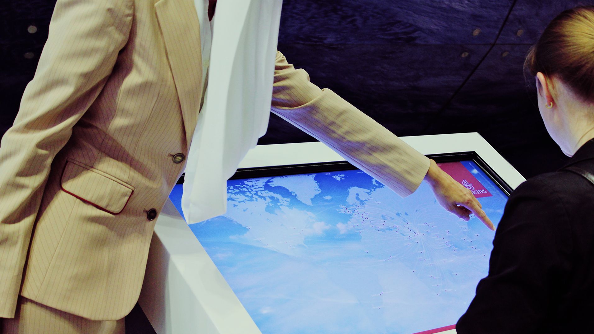 Two visitors exploring destinations together on a large horizontal touchscreen.
