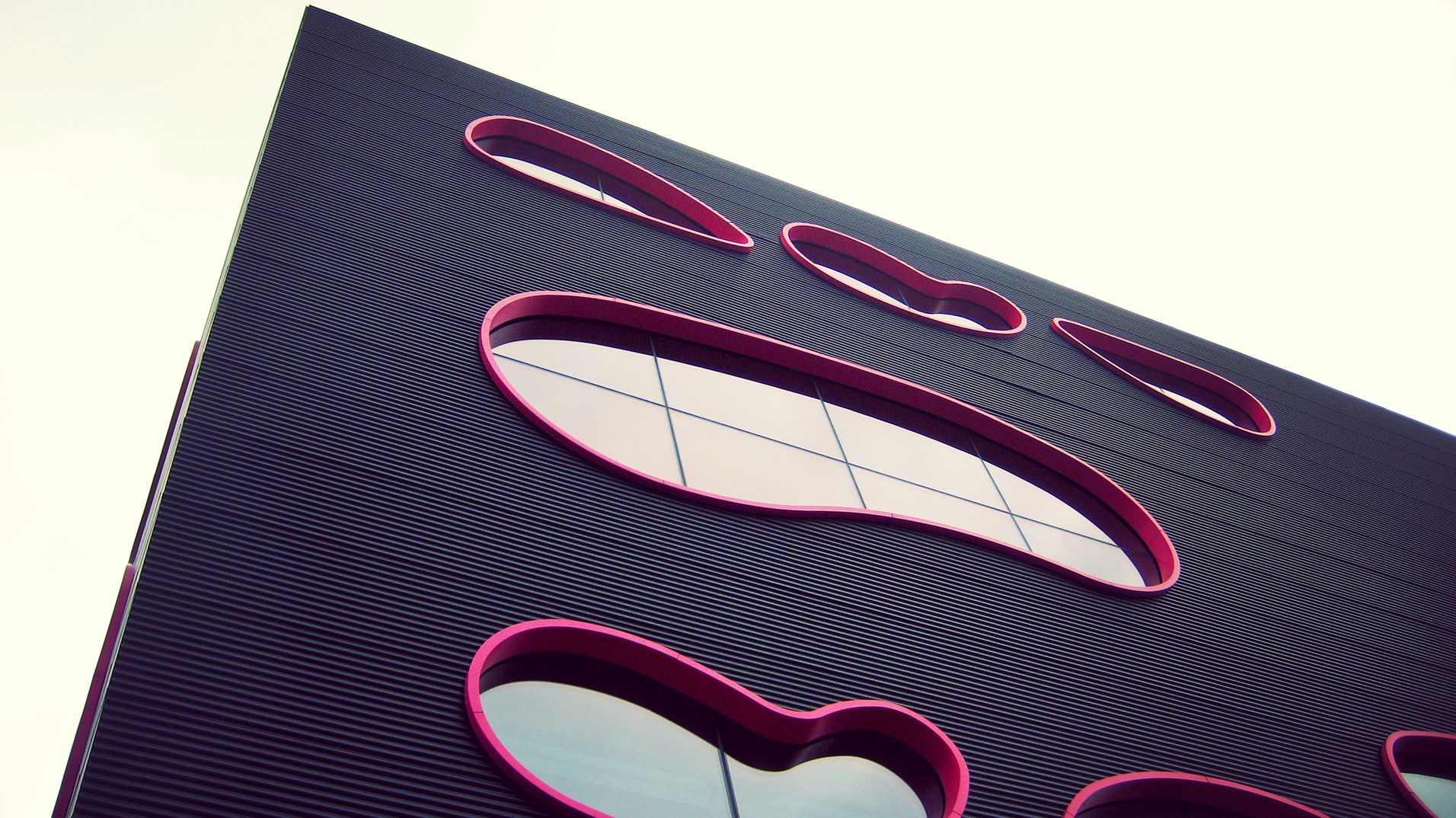 The Public gallery's dark exterior with organic windows outlined in pink.