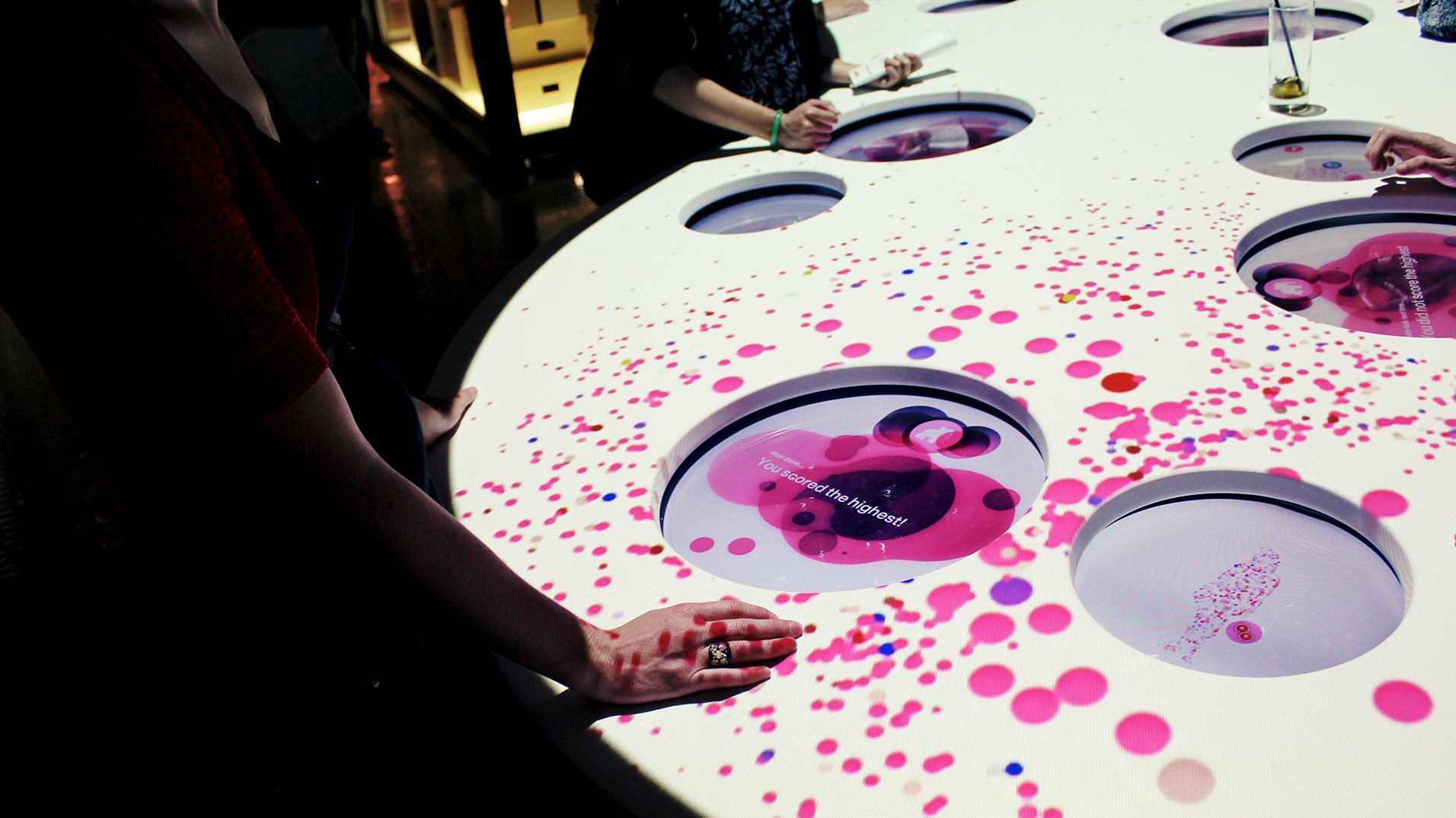 Visitors using circular interfaces embedded in the illuminated Content Heart table.
