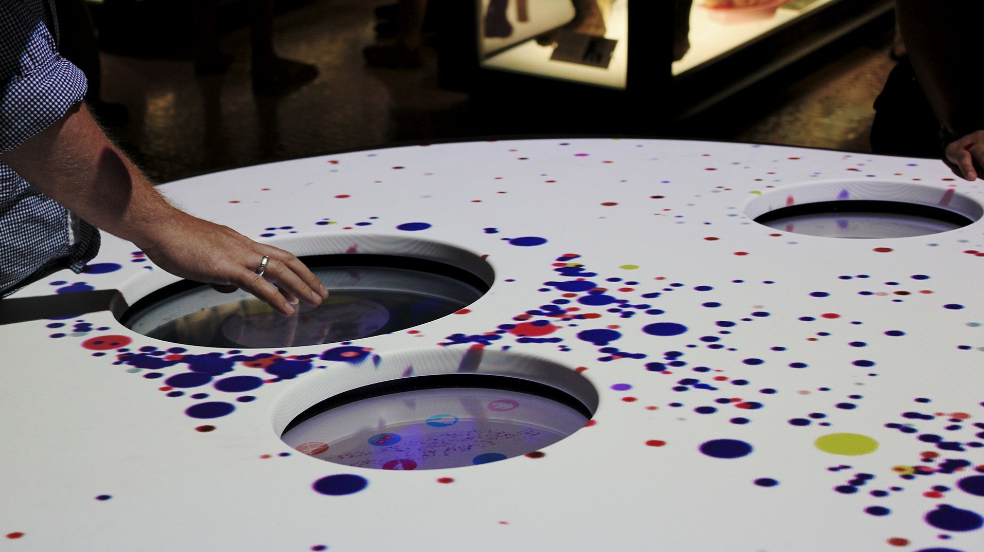 A visitor reaching into one of the circular touchscreen interfaces.