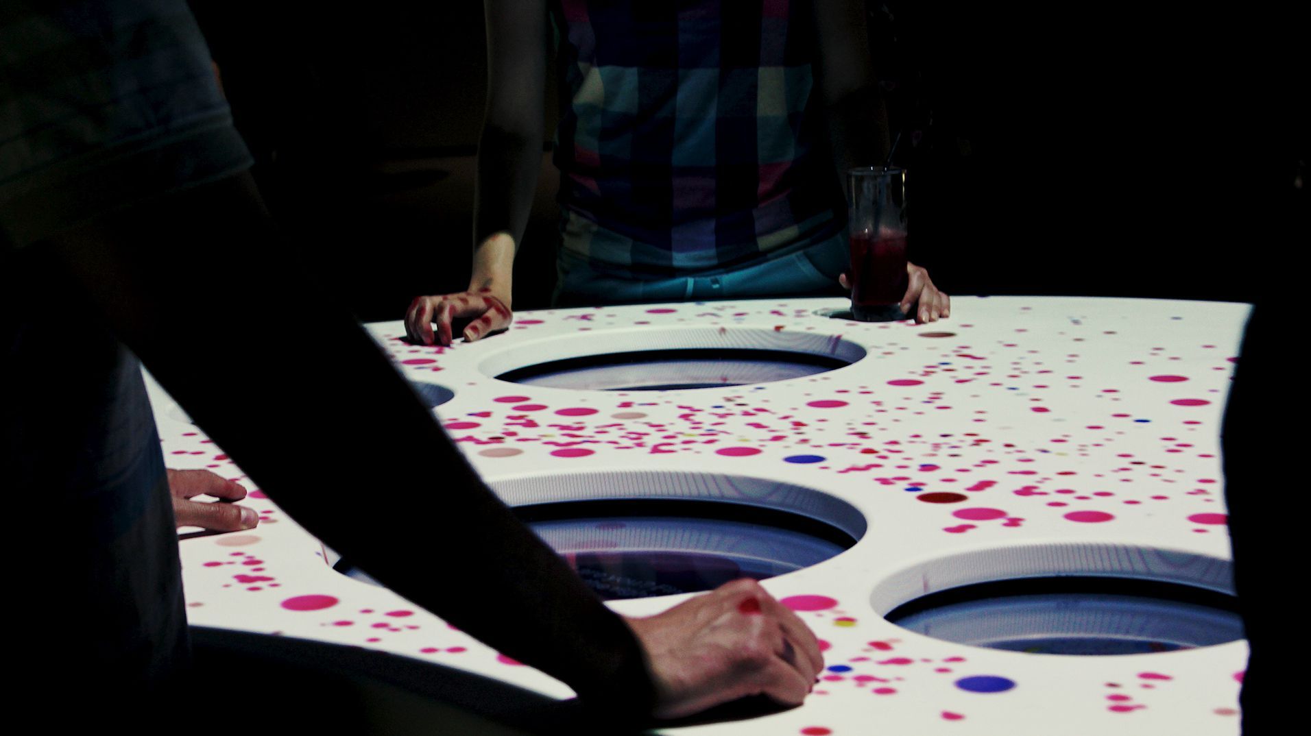 A visitor making a selection as pink data spreads across the interactive table.